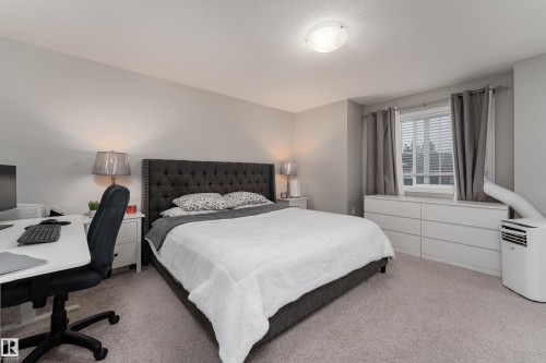 Carpeted bedroom featuring a window with blinds, a built-in recessed light, and neutral wall tones - 9468 209 St, Edmonton, AB 
