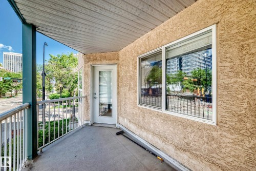Private balcony featuring a textured stucco exterior, white metal railing, and a glass-paneled door - 214 9938 104 Street, Edmonton, AB 