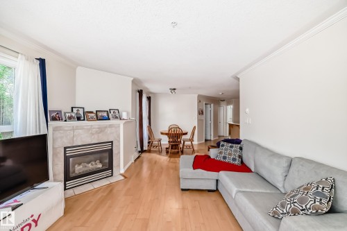 Living area with wood-finish flooring, a tile-surround fireplace, and crown molding - 214 9938 104 Street, Edmonton, AB 