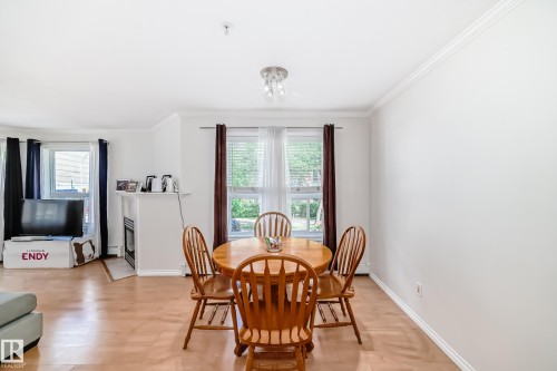 Dining area featuring wood-finish flooring, white walls, and a contemporary ceiling fixture - 214 9938 104 Street, Edmonton, AB 