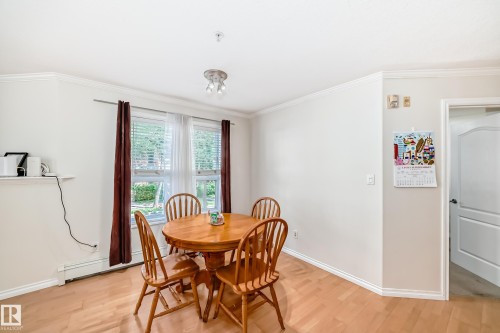 Dining area featuring wood-finish flooring and crown molding - 214 9938 104 Street, Edmonton, AB 