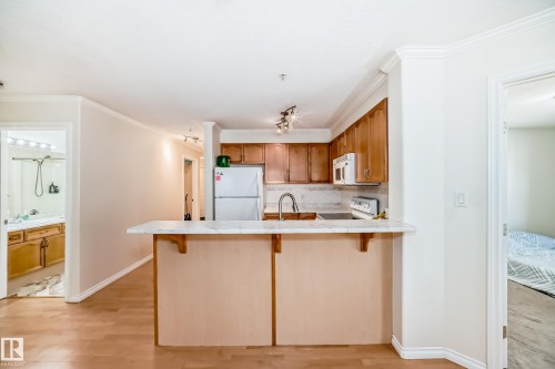 Kitchen featuring wood-finish cabinetry, white appliances, and a light-toned countertop - 214 9938 104 Street, Edmonton, AB 