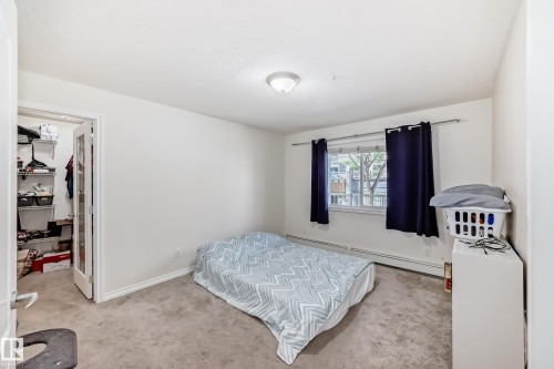 Carpeted room with a ceiling-mounted light fixture and white baseboards - 214 9938 104 Street, Edmonton, AB 