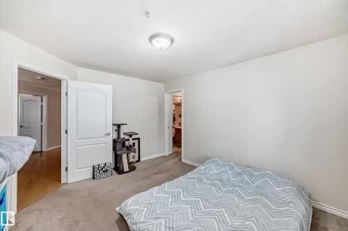 Carpeted room with light neutral walls and a ceiling-mounted flush light fixture - 214 9938 104 Street, Edmonton, AB 