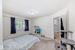 Carpeted room featuring a window with white trim, baseboard heating, a ceiling-mounted light fixture, and a solid-core door - 