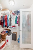Walk-in closet featuring wire shelving, wall-mounted hanging rods, and light-toned carpet flooring - 