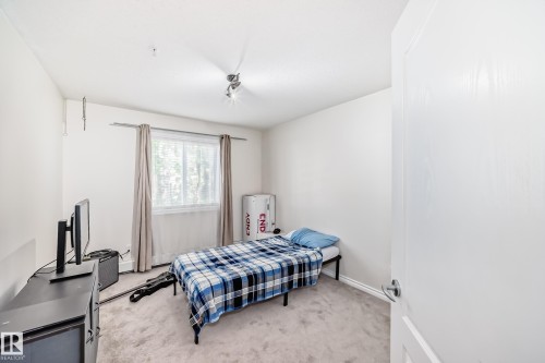Light-colored carpeted flooring, white walls, and a window with natural light - 214 9938 104 Street, Edmonton, AB 
