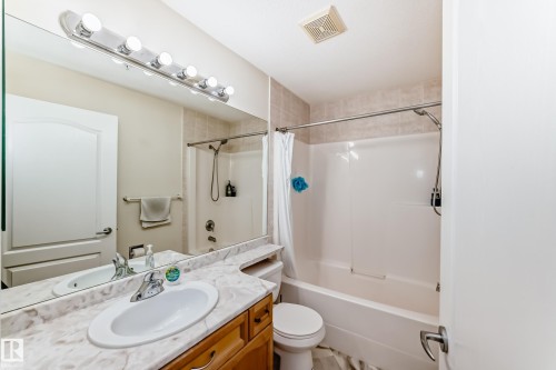 Bathroom featuring a vanity with an integrated sink, a large mirror, and a full shower-tub combination - 214 9938 104 Street, Edmonton, AB 