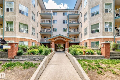 Melrose Manor apartment building featuring a stucco exterior with brick accents, multiple private balconies, and a covered main entrance - 214 9938 104 Street, Edmonton, AB 