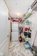 Laundry area featuring a stacked washer and dryer unit, wire shelving, and wood-finish flooring with a herringbone pattern - 