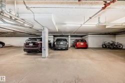 Underground parking space featuring concrete flooring, overhead fluorescent lighting, and exposed ceiling pipes - 
