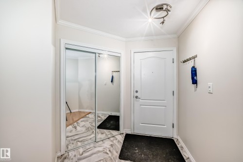 Entryway featuring a contemporary track light fixture, crisp white trim, and a mirrored sliding closet door - 214 9938 104 Street, Edmonton, AB 