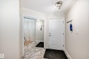 Entryway featuring a contemporary track light fixture, crisp white trim, and a mirrored sliding closet door - 214 9938 104 Street, Edmonton, AB 