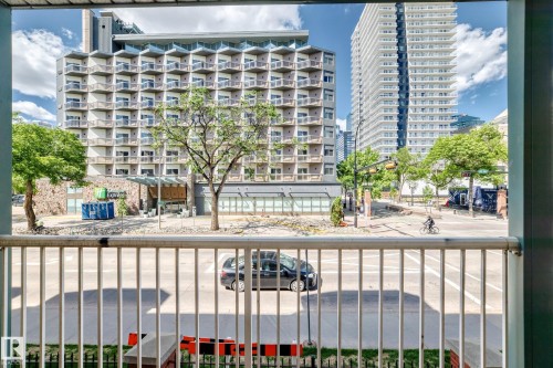 Balcony railing framing a streetscape with multiple high-rise buildings and mature trees - 214 9938 104 Street, Edmonton, AB 