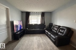 Living area featuring light gray walls, textured ceiling, a white paneled door, and a window with blinds and drapes - 