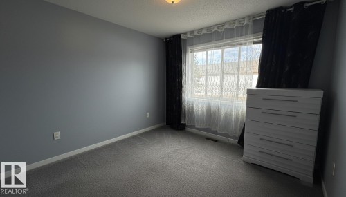Carpeted room with a ceiling-mounted light fixture and a window featuring white trim - 133 301 Clareview Station Drive, Edmonton, AB 
