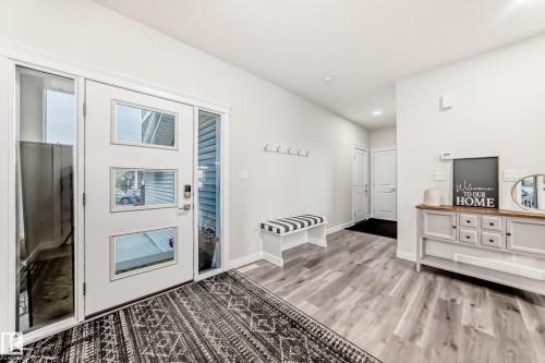 Entryway featuring a white door with rectangular lites, sidelights, wood-finish flooring, and light-toned walls - 589 Boulder Wynd, Leduc, AB - Indoor Photo Showing Other Room With Fireplace