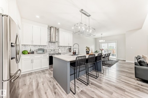 Contemporary kitchen featuring white cabinetry, a tiled backsplash, and stainless steel appliances including a range hood - 589 Boulder Wynd, Leduc, AB - Indoor Photo Showing Kitchen With Upgraded Kitchen