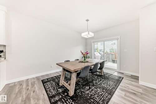 Dining area featuring wood-finish flooring, a contemporary ceiling light fixture, a built-in cabinet with a stone countertop, and sliding glass doors providing outdoor access - 589 Boulder Wynd, Leduc, AB - Indoor Photo Showing Dining Room