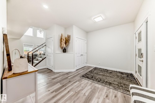 Entryway featuring light wood-finish flooring, a white paneled door with frosted glass inserts, and a contemporary flush-mount ceiling light - 589 Boulder Wynd, Leduc, AB - Indoor Photo Showing Other Room