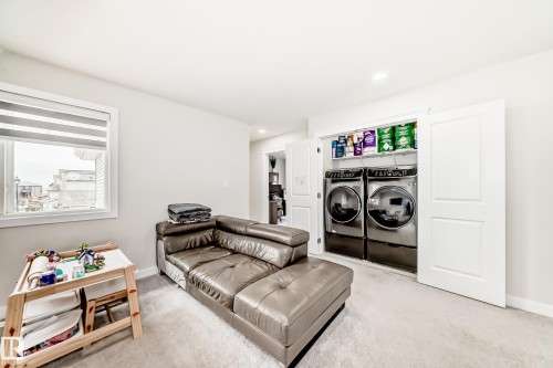 Dedicated laundry closet featuring a stackable washer and dryer set, integrated shelving, and white bi-fold doors - 589 Boulder Wynd, Leduc, AB - Indoor Photo Showing Laundry Room
