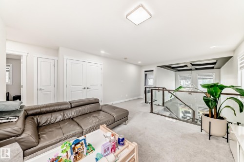 Carpeted common area featuring a glass and wood-finish railing, white trim, recessed lighting, and a square ceiling light fixture - 589 Boulder Wynd, Leduc, AB - Indoor Photo Showing Other Room