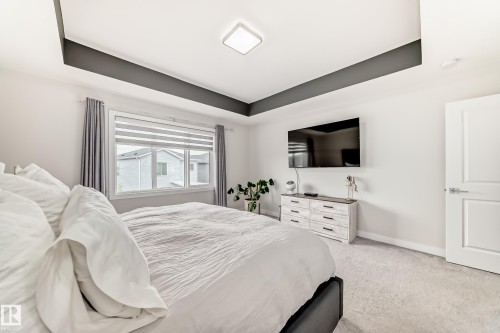 Bedroom featuring a tray ceiling with a dark accent band, light-toned walls, and a large window with blinds - 589 Boulder Wynd, Leduc, AB - Indoor Photo Showing Bedroom