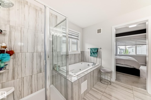 Contemporary bathroom featuring a jetted tub, a separate shower with a glass enclosure, and large format tile flooring - 589 Boulder Wynd, Leduc, AB - Indoor Photo Showing Bathroom