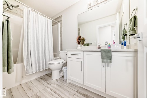 Contemporary bathroom featuring a white vanity with a light-toned countertop, a large wall-mounted mirror, and a built-in shower/tub combination - 589 Boulder Wynd, Leduc, AB - Indoor Photo Showing Bathroom