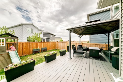 Expansive backyard featuring a light gray composite deck, a dark-framed gazebo, and a wood privacy fence - 589 Boulder Wynd, Leduc, AB - Outdoor With Deck Patio Veranda With Exterior