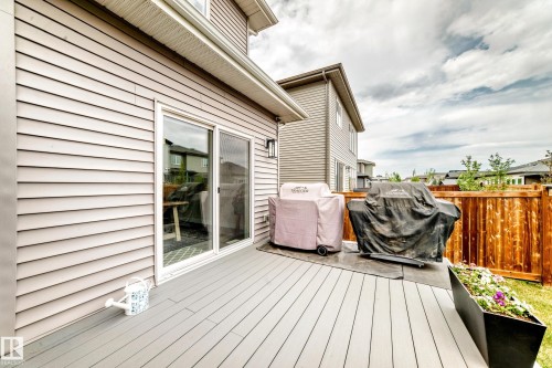 Spacious composite deck featuring a sliding glass door entry, exterior wall lighting, and a stained wood fence - 589 Boulder Wynd, Leduc, AB - Outdoor With Exterior