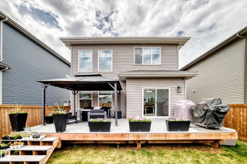 Spacious outdoor deck featuring light-toned decking, wooden privacy fencing, and a ground-level patio with steps - 589 Boulder Wynd, Leduc, AB - Outdoor With Deck Patio Veranda