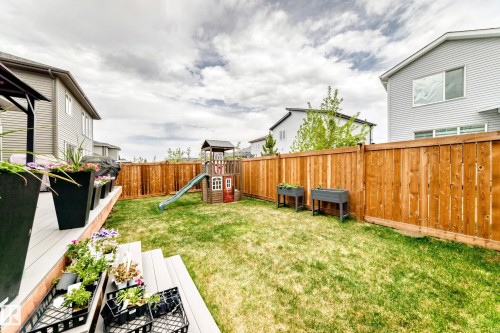Expansive backyard featuring a manicured lawn, full privacy fencing, and a multi-level deck with built-in stairs - 589 Boulder Wynd, Leduc, AB - Outdoor