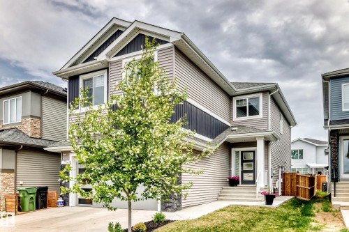 Contemporary two-story exterior featuring siding in varied tones, a black panel garage door, and a covered entry with a multi-pane door - 589 Boulder Wynd, Leduc, AB - Outdoor