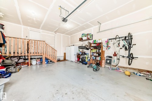 Spacious garage featuring a concrete floor, overhead lighting, and an automatic garage door opener - 589 Boulder Wynd, Leduc, AB - Indoor Photo Showing Garage