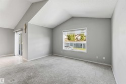 Vaulted ceiling room featuring light gray walls and patterned carpeting - 