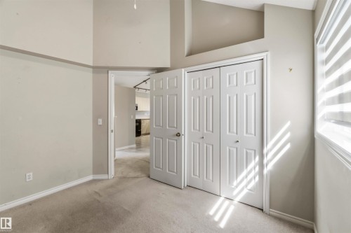 Carpeted interior space with a bi-fold closet door, neutral wall tones, and a window with horizontal blinds - 2012 35A Avenue, Edmonton, AB 