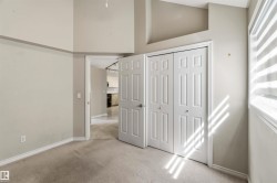 Carpeted interior space with a bi-fold closet door, neutral wall tones, and a window with horizontal blinds - 