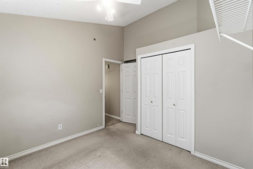 Carpeted room featuring a ceiling fan, light gray wall paint, white baseboards, and a bi-fold closet with white doors - 2012 35A Avenue, Edmonton, AB 