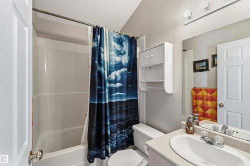 Bathroom featuring a white tub/shower combination, white toilet, and a vanity with a light-colored countertop and integrated sink - 2012 35A Avenue, Edmonton, AB 