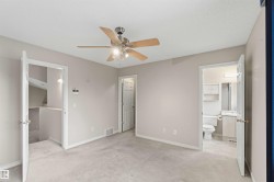 Carpeted interior space featuring a ceiling fan with light fixture, neutral wall paint, and white trim - 