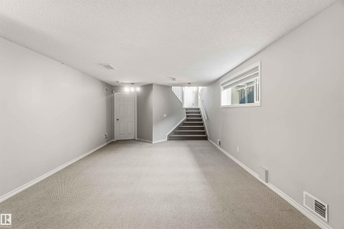 Spacious room featuring light gray carpeting, neutral wall paint, and white baseboards - 2012 35A Avenue, Edmonton, AB 