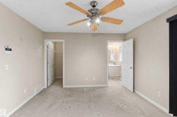 Carpeted room featuring a ceiling fan with light fixture, neutral wall color, and white trim - 