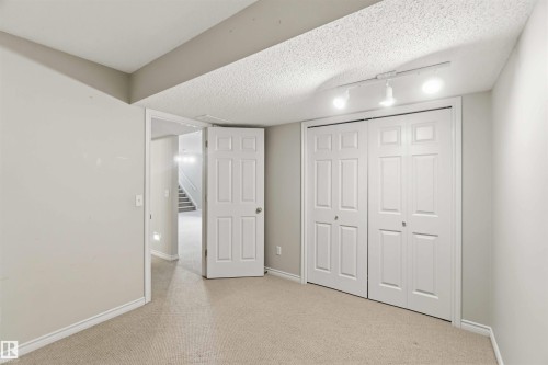 Carpeted room featuring light gray walls, white trim, and a bi-fold closet with panel doors - 2012 35A Avenue, Edmonton, AB 