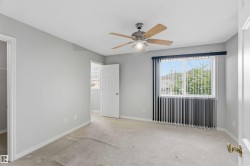 Room featuring neutral-toned walls, a ceiling fan with light fixture, and a window with vertical blinds - 