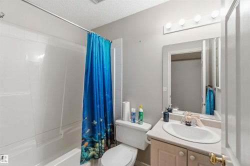 Bathroom featuring a white bathtub and shower surround, light gray walls, and a vanity with an integrated sink and light-toned cabinetry - 2012 35A Avenue, Edmonton, AB 