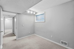 Carpeted room featuring a window with horizontal blinds, track lighting, and a baseboard vent - 