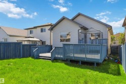 Expansive backyard featuring a manicured lawn, a full wooden deck with railings, and privacy fencing - 
