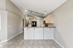 Open-concept kitchen area featuring a breakfast bar with a light wood-finish countertop, light wood cabinetry, and track lighting - 