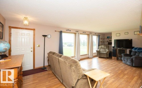 Spacious living area featuring wood-finish flooring, ample natural light from multiple windows, and a panel-style entry door with wood trim - 57532 Rg Rd 270, Rural Westlock County, AB 